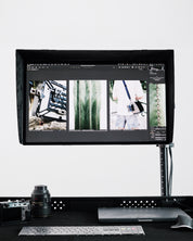 Computer monitor displaying images on a desk with a camera and keyboard.