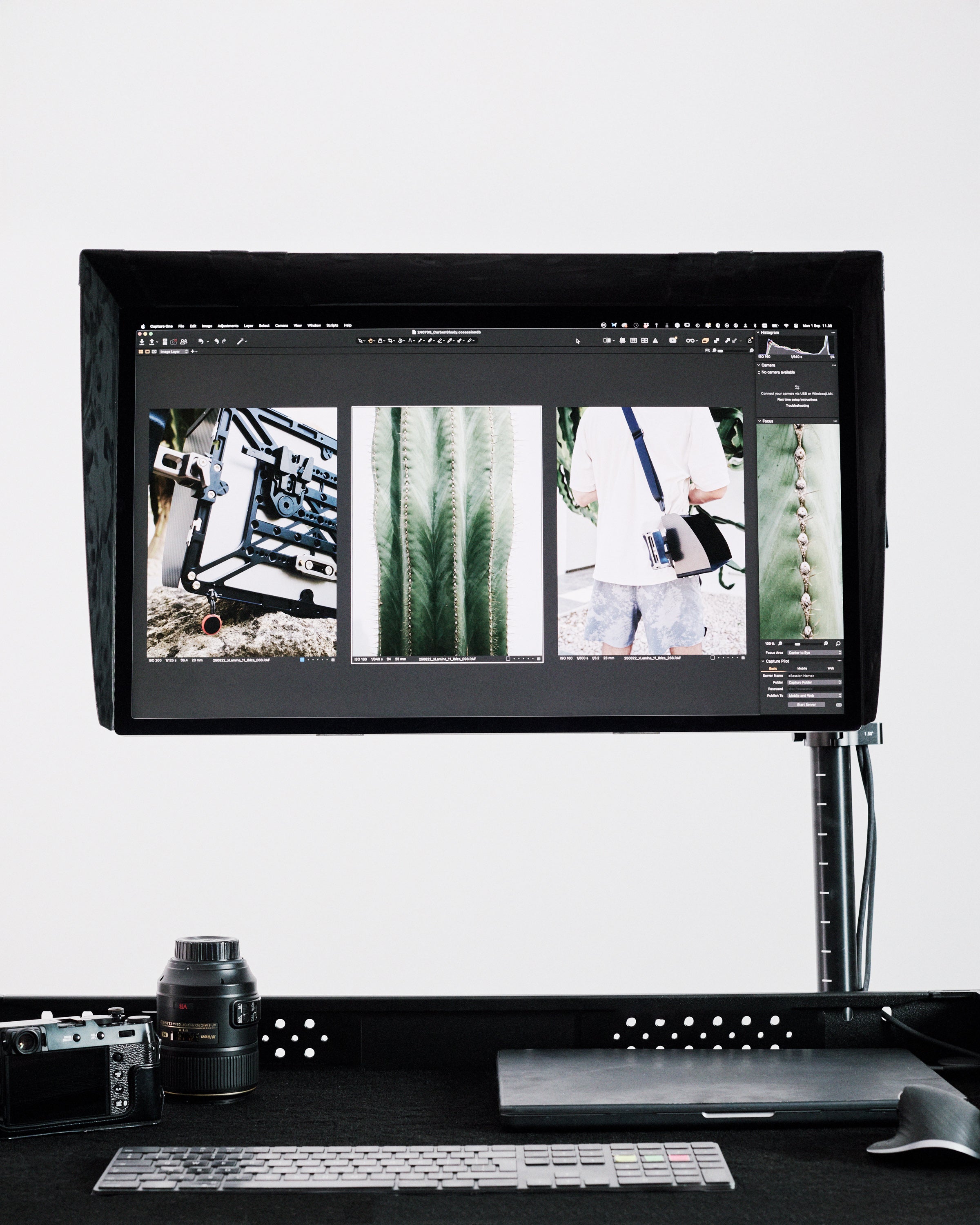 Computer monitor displaying images on a desk with a camera and keyboard.